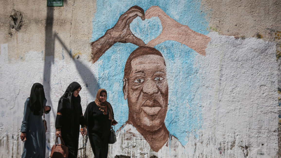 GAZA CITY, GAZA - JUNE 16 : People walk past a mural of George Floyd, an unarmed black man who died after being pinned down by a white police officer in Minneapolis, Minnesota, painted by a Palestinian artist on the wall in Gaza City, Gaza on June 16, 2020. (Photo by Ali Jadallah/Anadolu Agency via Getty Images)
