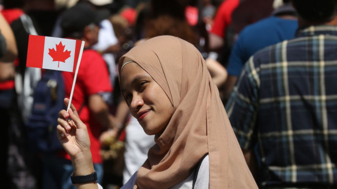 A Muslim woman holds a Canadian flag during the multicultural Canada Day celebration in Toronto, Ontario, Canada on 1 July, 2019. [Getty]