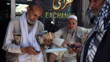 Afghan money changers calculate at the currency exchange Sarayee Shahzada market in Kabul