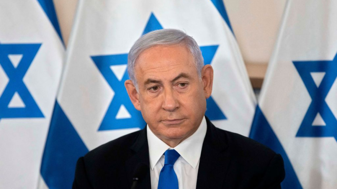 Benjamin Netanyahu in front of three Israeli flags