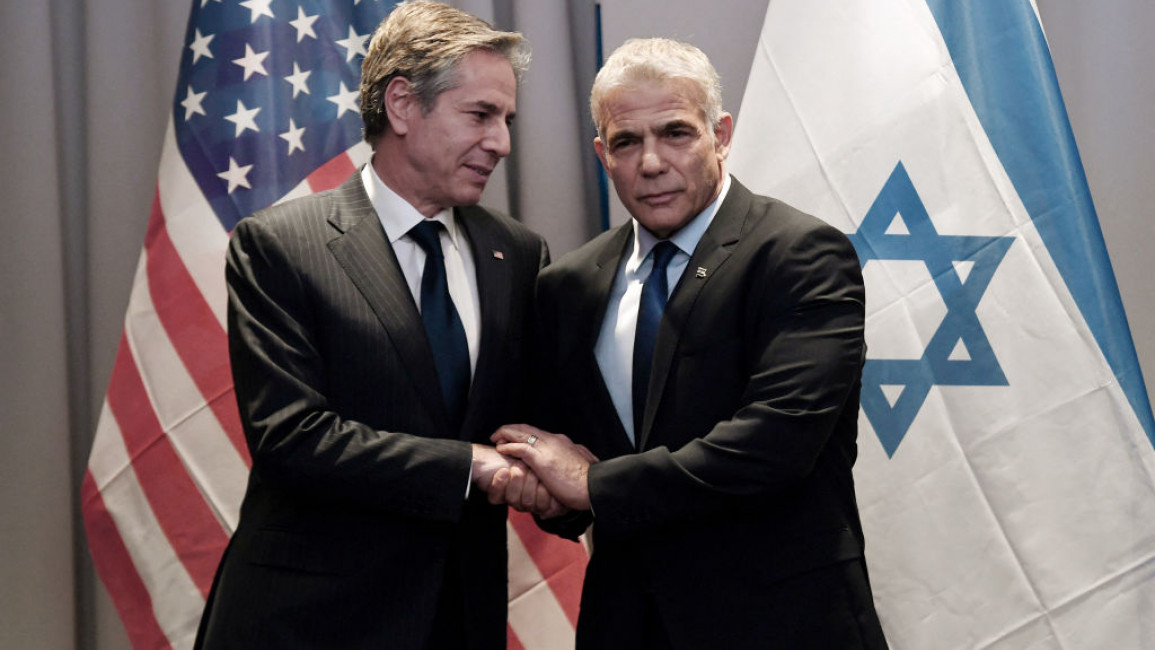 Antony Blinken (left) with Yair Lapid (right) against a backdrop of the US and Israeli flags