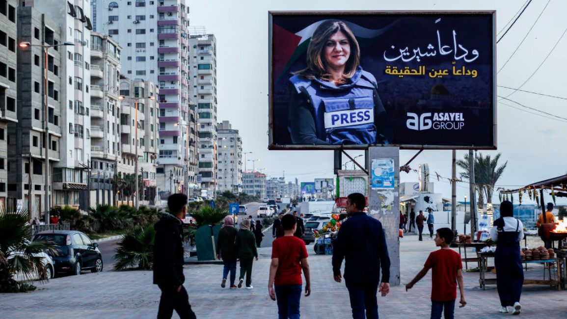 People looking up at a billboard containing the image of Shireen Abu Akleh, the Palestinian journalist killed by Israeli forces on 11 May 2022