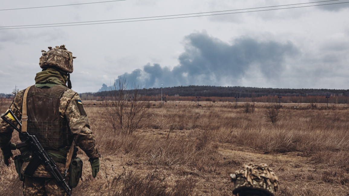 Ukrainian army soldier watches the smoke from shelling