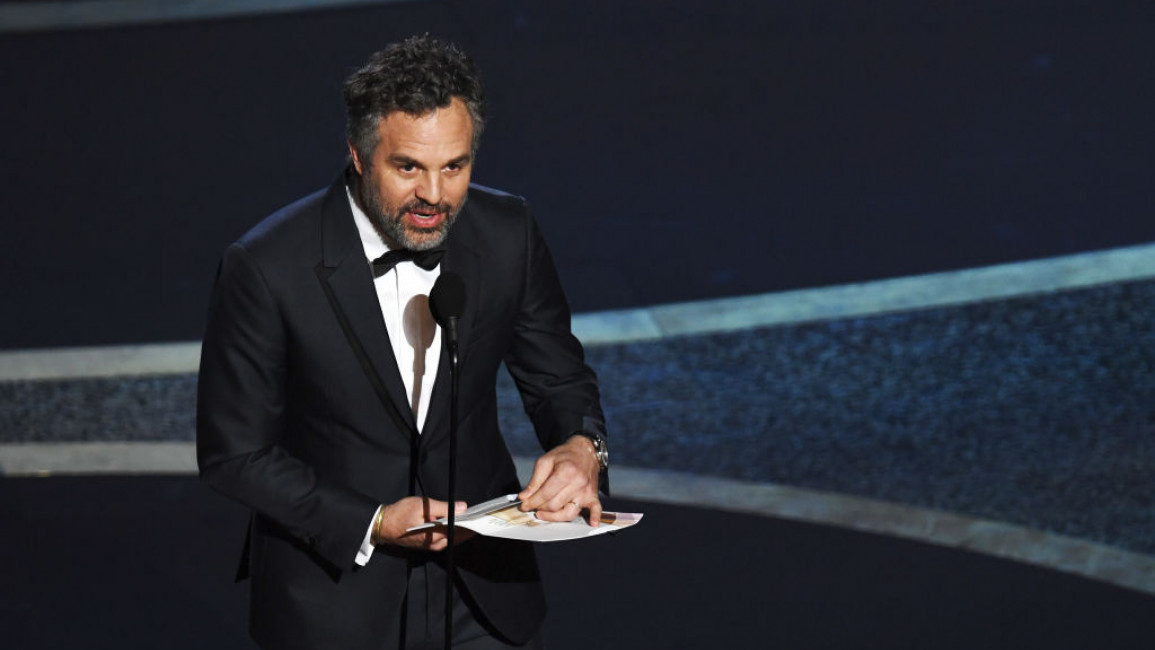 Mark Ruffalo in a suit, speaking into a microphone