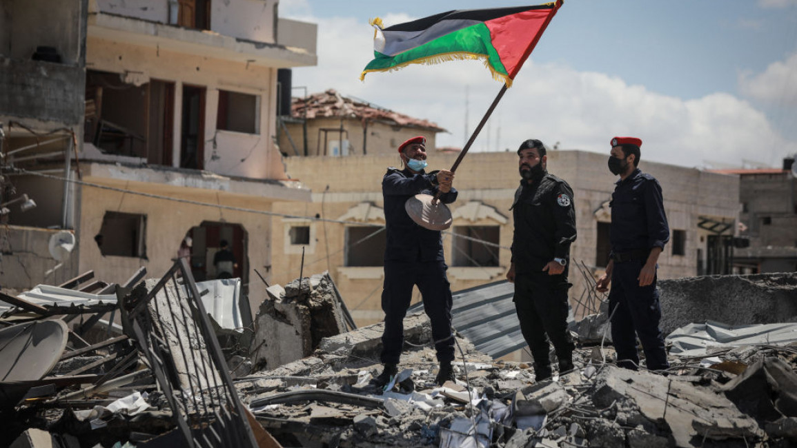 Palestinian policemen walk on the rubble of Arafat City, Gaza's police headquarters in Gaza City on May 22, 2021, 