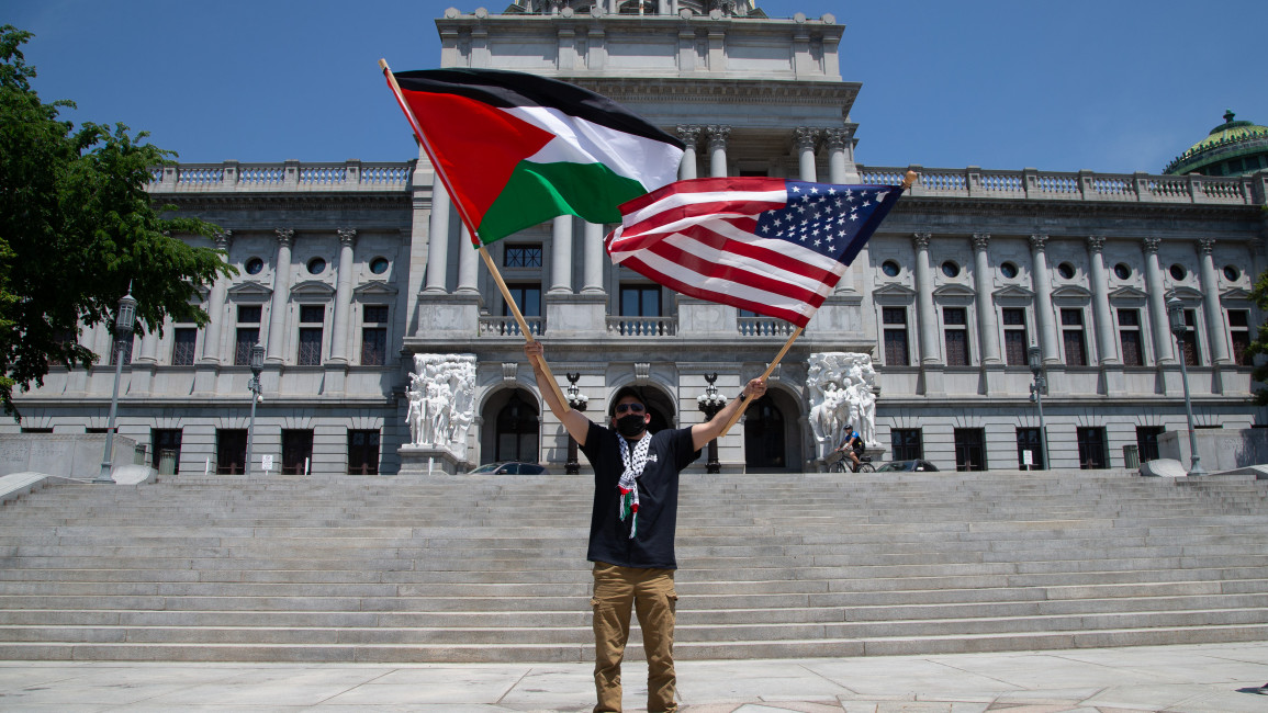 A pro-Palestine demonstrator waves a Palestine flag and an American flag at the Pennsylvania State Capitol [Getty]