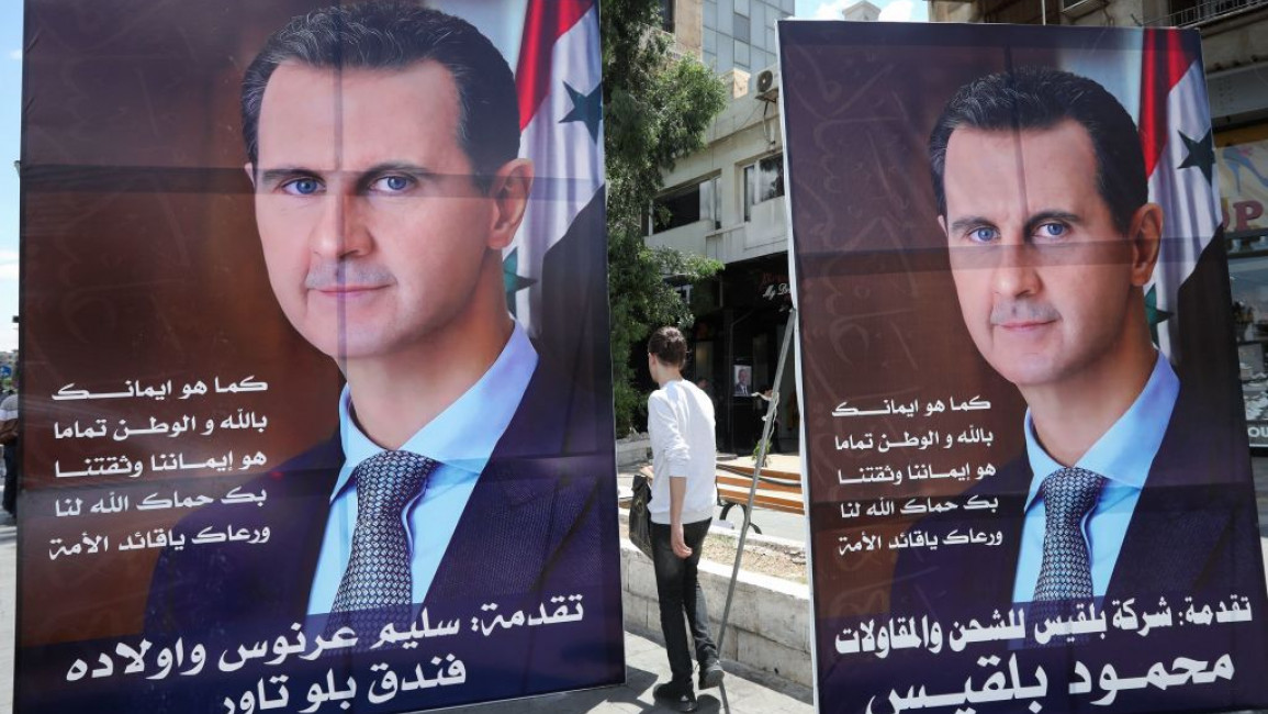 People walk next to election campaign billboards in Damascus depicting Syrian President Bashar al-Assad. [Getty]