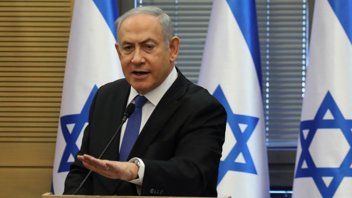 Benjamin Netanyahu in front of three Israeli flags