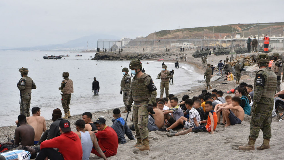 Migrants, including minors, who arrived swimming at the Spanish enclave of Ceuta, are guarded by Spanish soldiers on 18 May, 2021. [Getty]