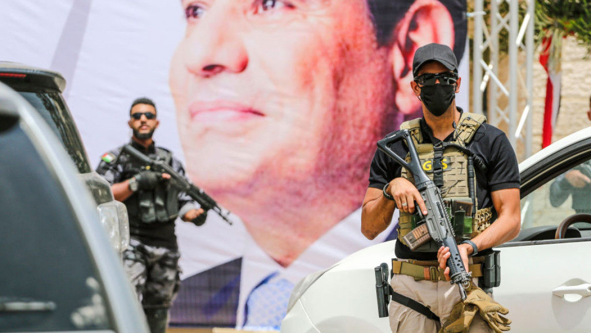 Hamas fighters stand guard near a poster showing Egyptian President Sisi in Gaza [Getty]