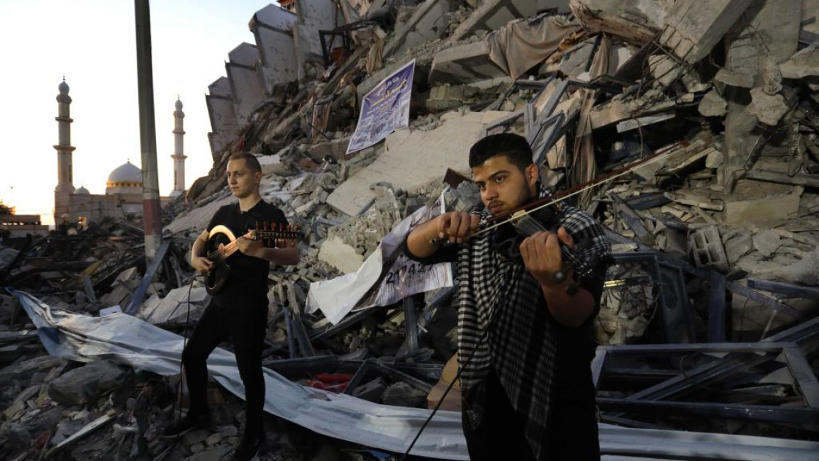 Palestinian musicians perform during a public concert outside the destroyed Hanadi apartment by Israeli attacks in Gaza on 2 June, 2021. [Getty]