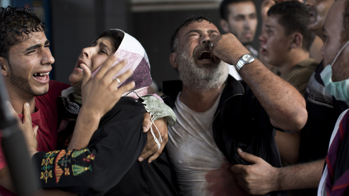 Palestinian mourners cry at Gaza City's al-Shifa hospital after an explosion killed at least seven children in a public playground in the beachfront Shati refugee camp on July 28, 2014. Palestinian medical sources blamed the killings on air strikes launched by the Israeli military, which in turn said Hamas had misfired its own rockets at the camp and at the Shifa hospital. AFP PHOTO/MAHMUD HAMS (Photo credit should read MAHMUD HAMS/AFP via Getty Images)