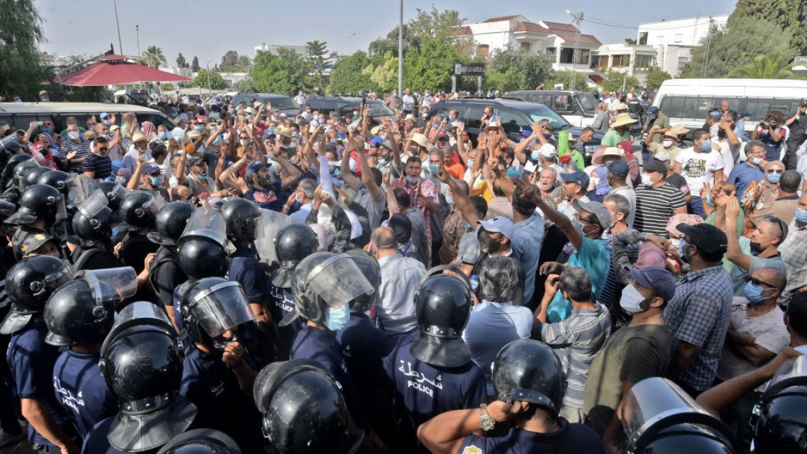 Tunisian security officers hold back protesters outside the parliament 