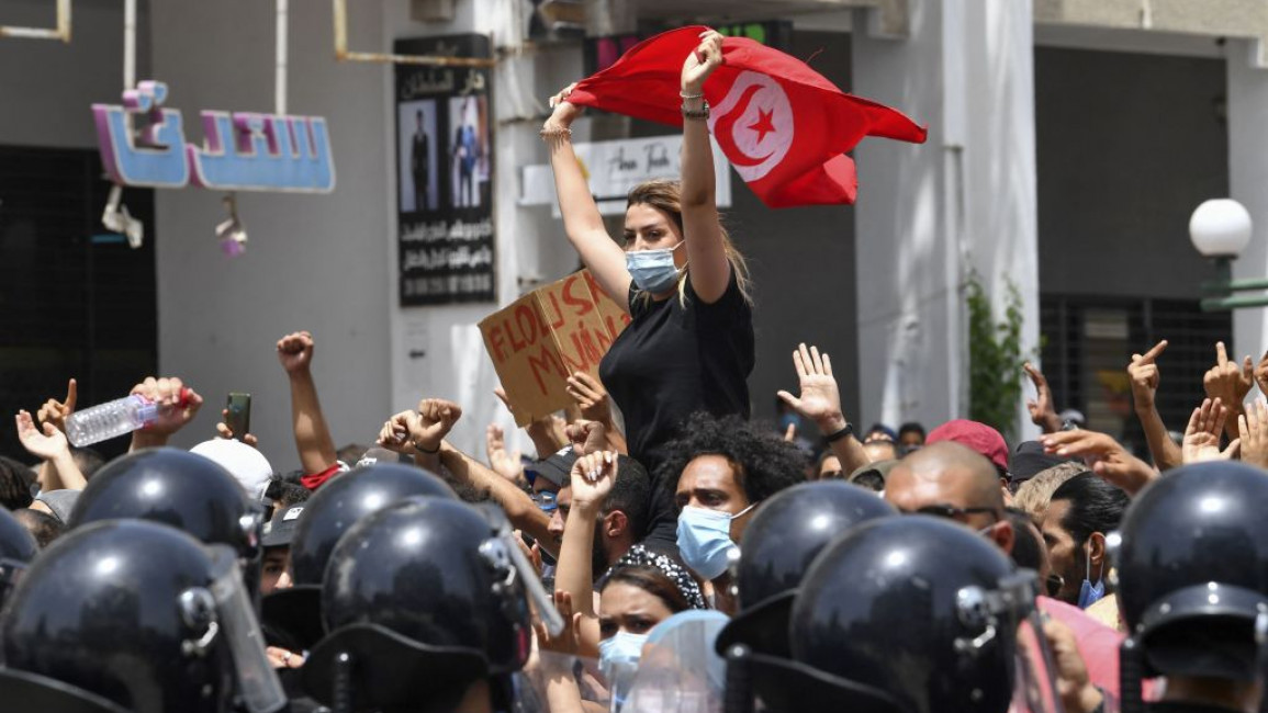 A Tunisian protester lifts a national flag at an anti-government rally as security forces block off the road in front of the Parliament in the capital Tunis on 25 July, 2021. [Getty]