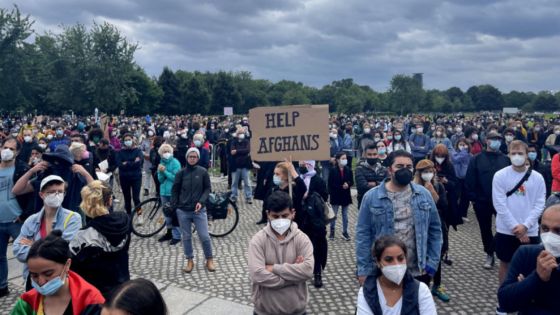 Demonstrators holding placards in front of the Reichstag building demand safe evacuation of Afghans who are desperate to get out the country after Taliban took control of the capital Kabul, on August 17, 2021
