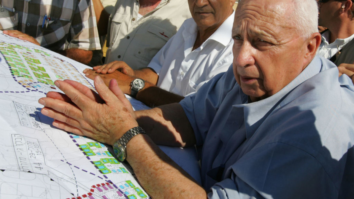 Then-Israeli Prime Minister Ariel Sharon (R) building temporary housing for settlers evacuated from the Gaza Strip under his Disengagement Plan on 5 July, 2005. [Getty]
