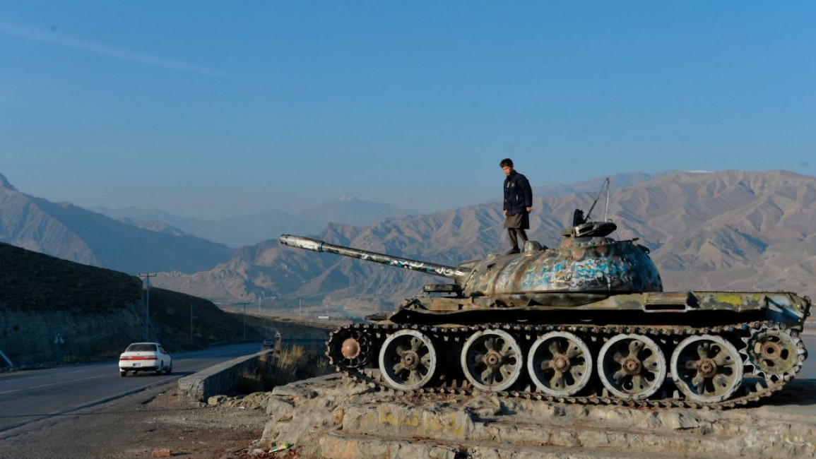 An Afghan boy plays on the wreckage of a Soviet-era tank alongside a road on the outskirts of Kabul. [Getty]