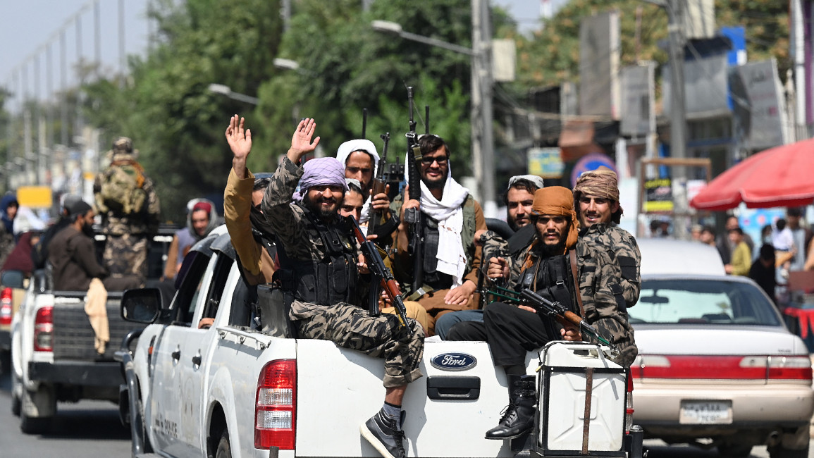 Taliban fighters wave as they patrol in a convoy along a street in Kabul [Getty]