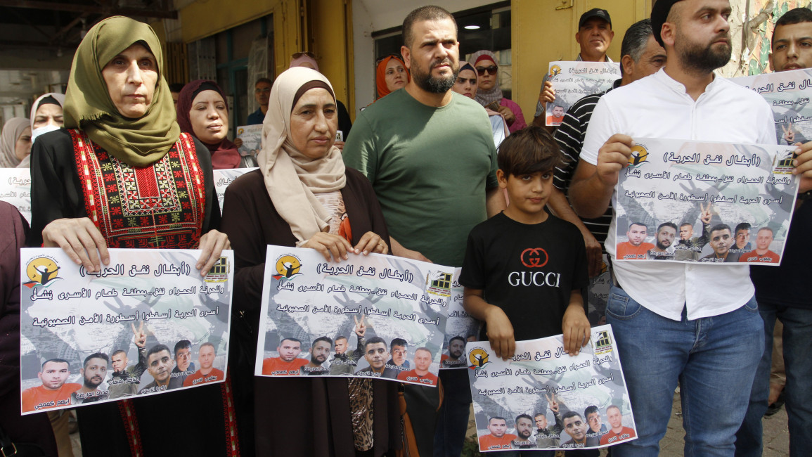 Palestinians seen holding portraits showing prisoners, Zakaria al-Zubaidi and the four prisoners who escaped [Getty]