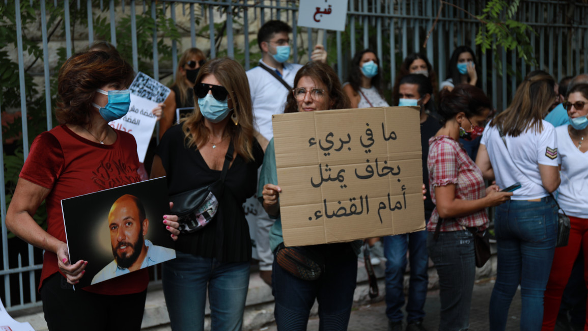 A woman holds a sign that reads "There are no innocents thatare afraid to appear before the court" at a protest in support of investigator Judge Tarek Bitar. (TNA) 