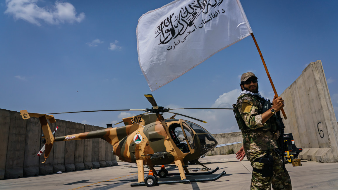 A Taliban fighter raises the movementÕs flag as they take a tour of the military assets that were left behind on the military airbase side of the Hamid Karzai International Airport, in the wake of the American forces completing their withdrawal from the country in Kabul, Afghanistan, Tuesday, Aug. 31, 2021. (MARCUS YAM / LOS ANGELES TIMES)