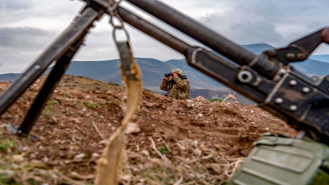 An Armenian soldier looks through binoculars along Azeri border