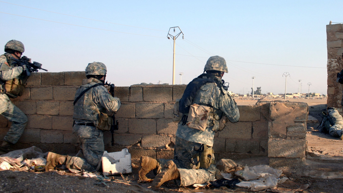 Three US soldiers taking cover behind a wall