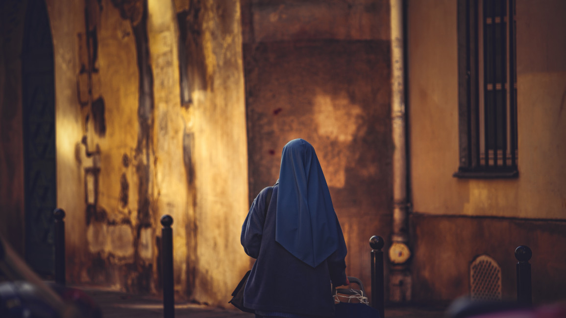 A woman wearing a blue hijab, shown from behind