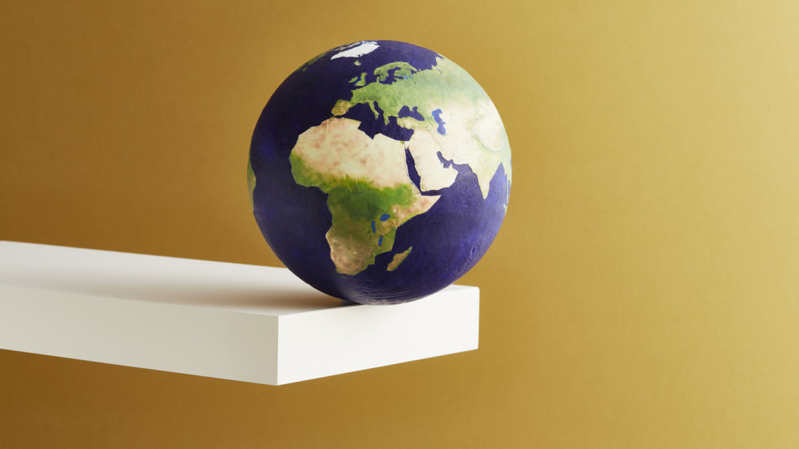 An image of the globe balanced on the edge of a white shelf
