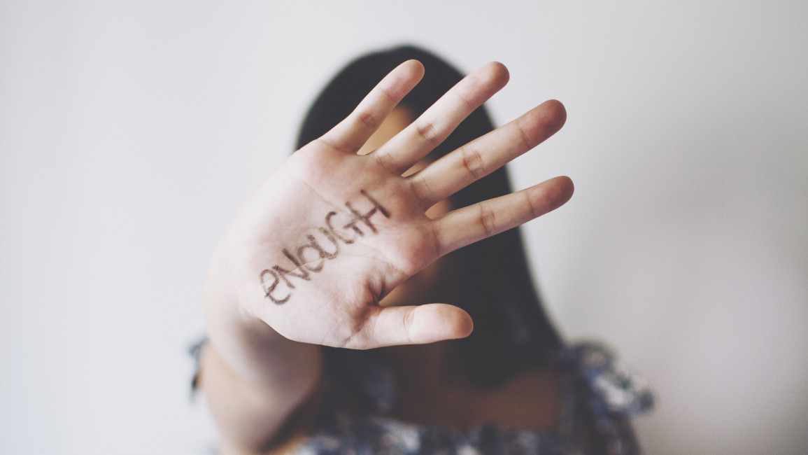 A woman holding her hand out with the word "enough" written on