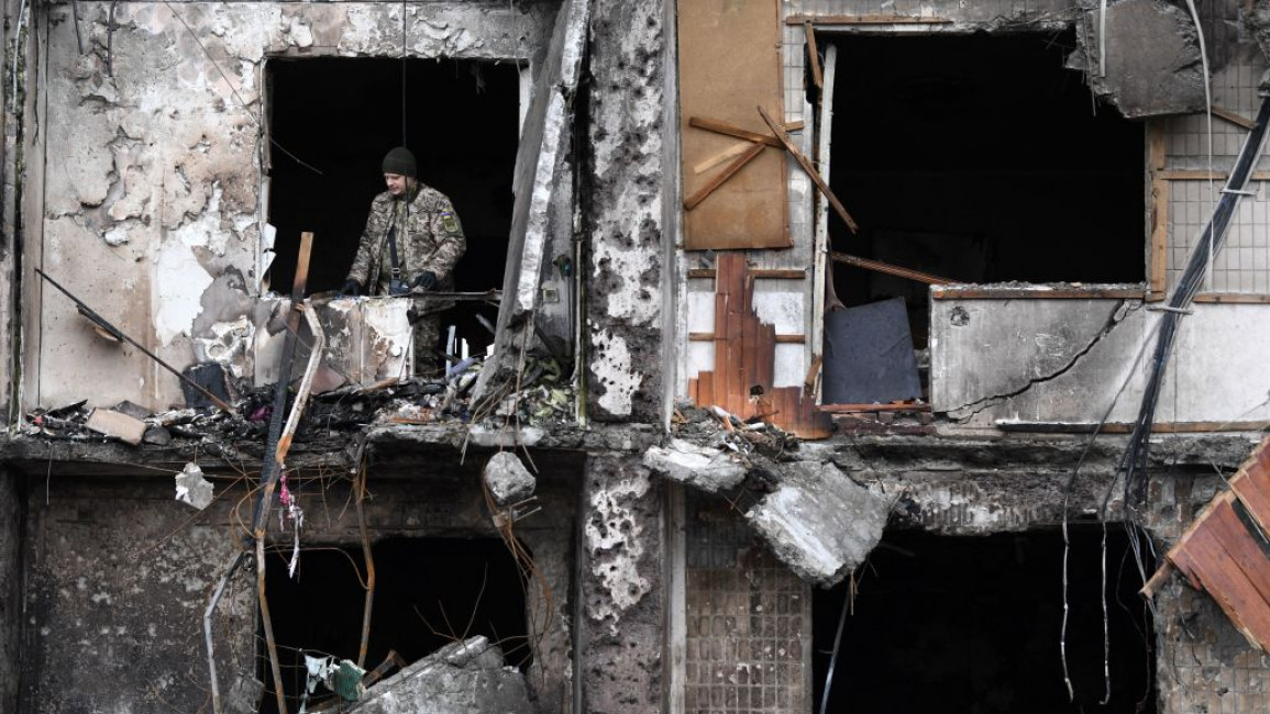 A damaged building in Ukraine with a Ukrainian soldier standing in the window