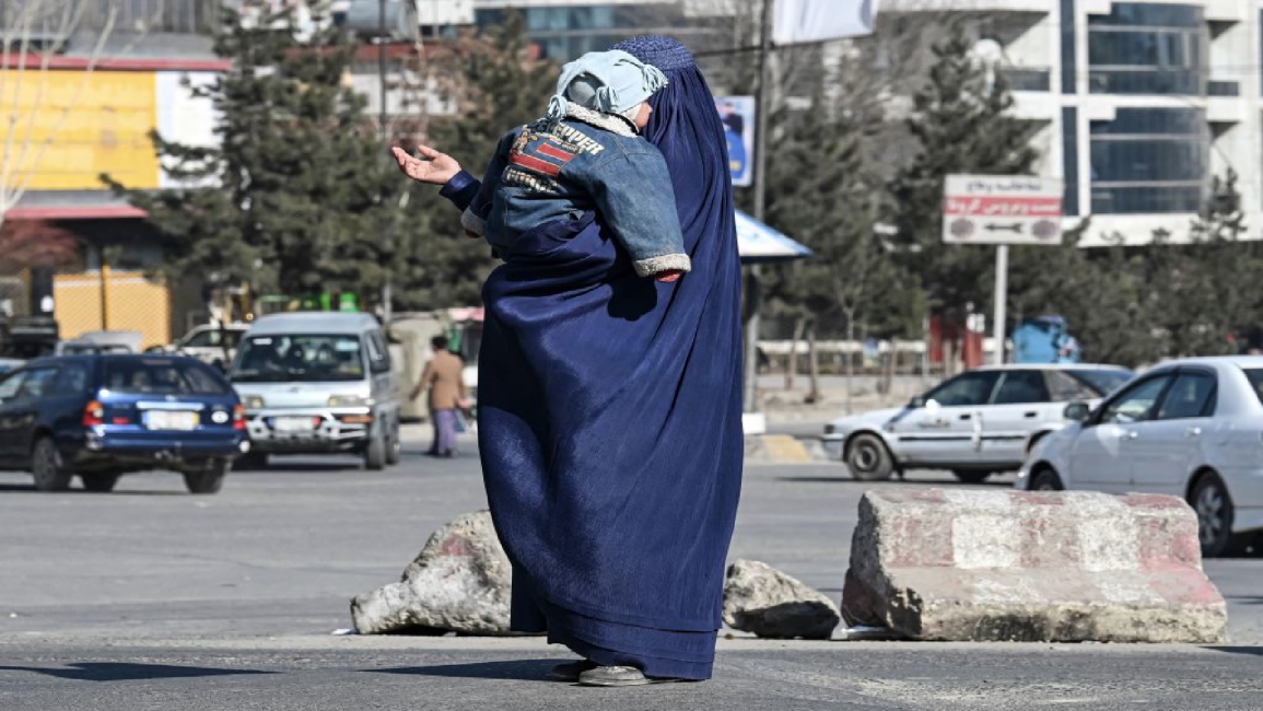 Afghan woman carrying her child begs on street