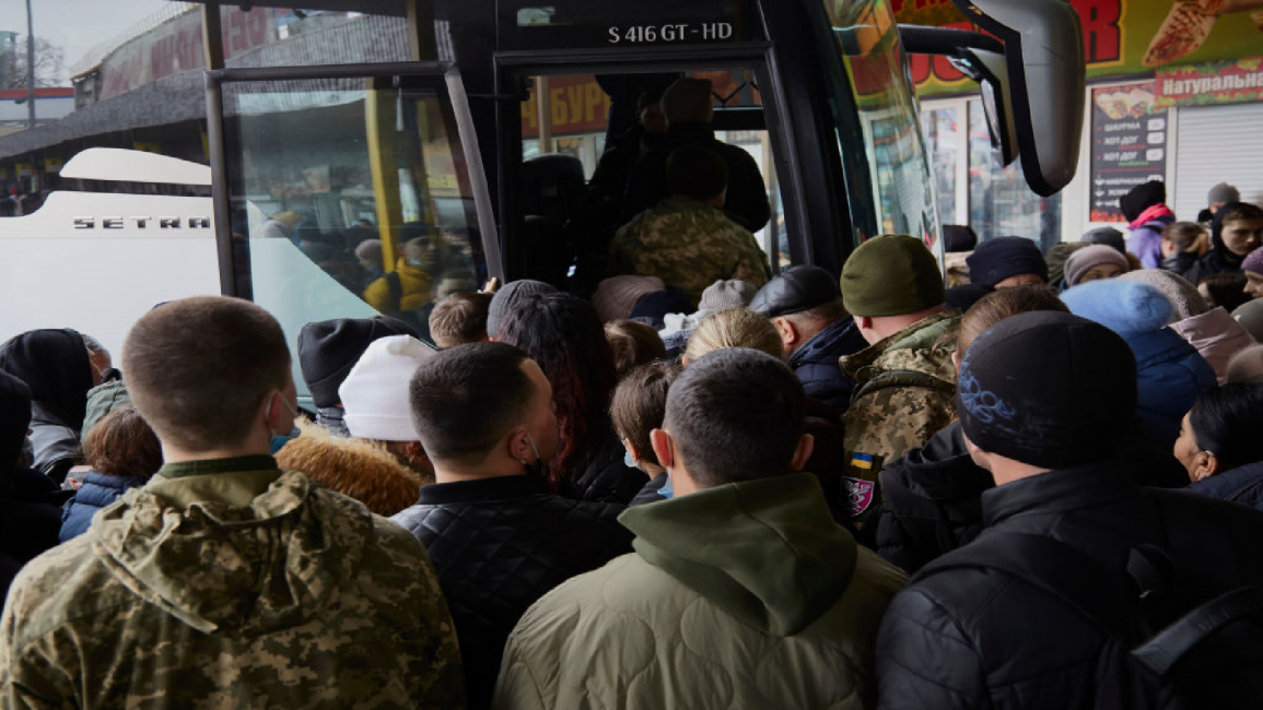 People and servicemen are boarding a bus to evacuate Kyiv