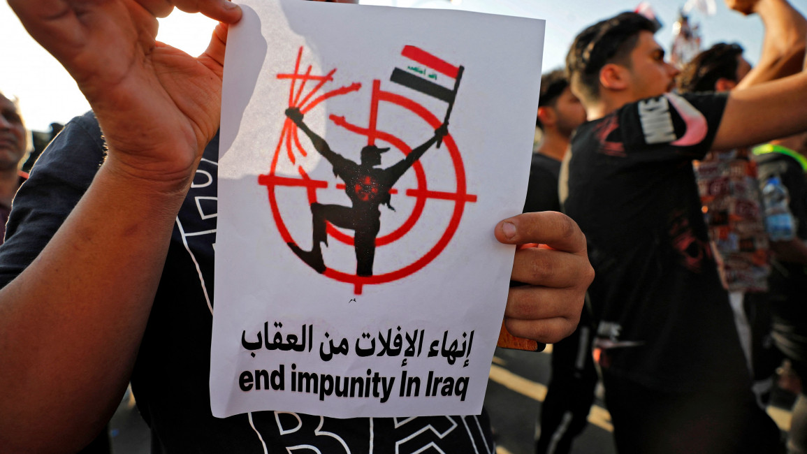 Iraqis lift placards as they demonstrate in Tahrir Square in Baghdad on May 25, 2021, to demand accountability for a recent wave of killings targeting activists. (Photo by AHMAD AL-RUBAYE / AFP) (Photo by AHMAD AL-RUBAYE/AFP via Getty Images)
