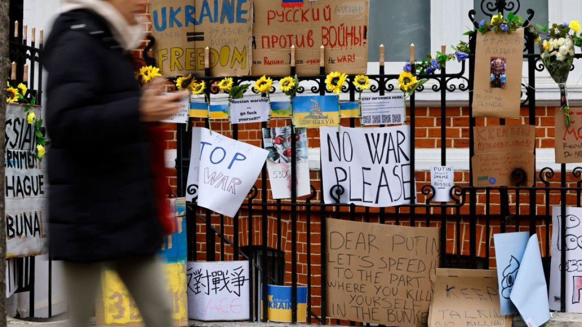 A pedestrian walks past placards tied to railings outside the Russian Embassy in London, on March 4, 2022 following Russia's invasion of Ukraine