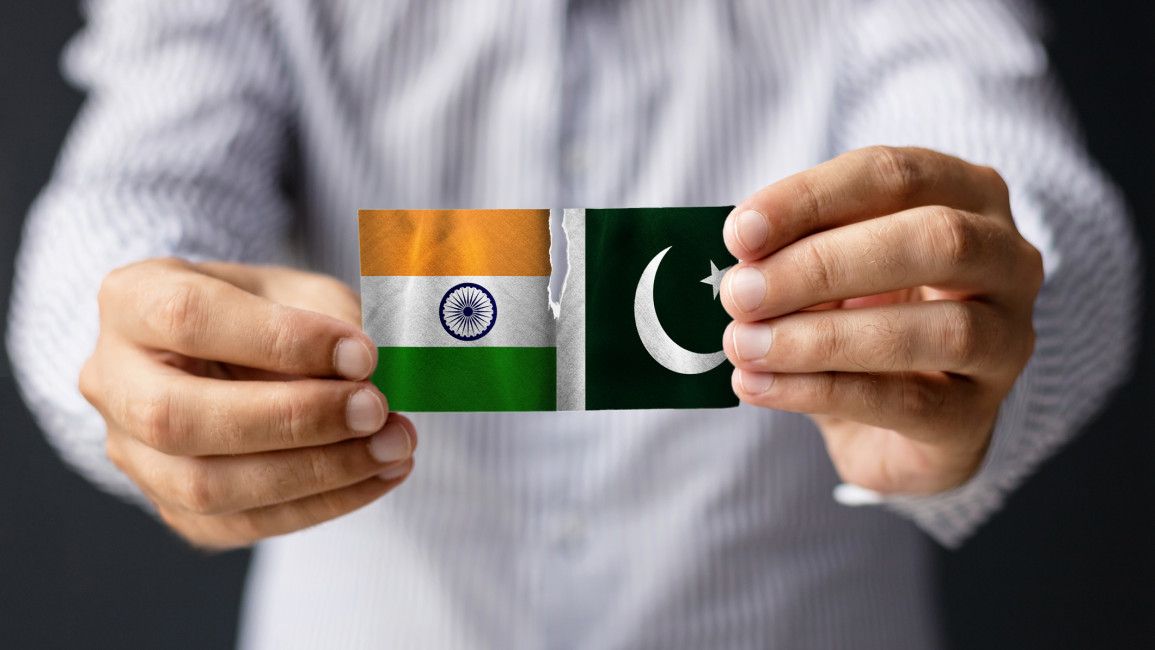 A man holding small paper Indian and Pakistani flags