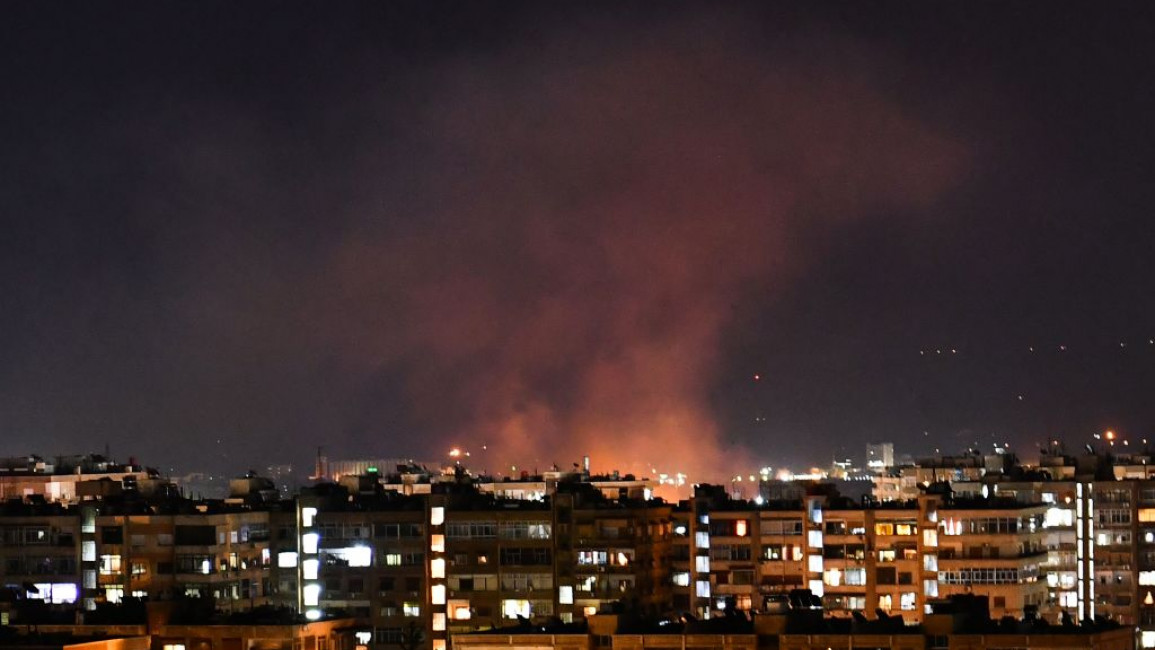 Red smoke or vapour rises above buildings after an Israeli airstrike south of Syria's capital, Damascus