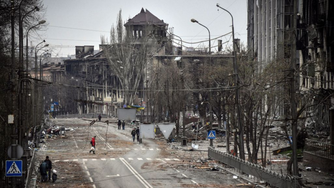 People walk through a severely damaged city of Mariupol in Ukraine
