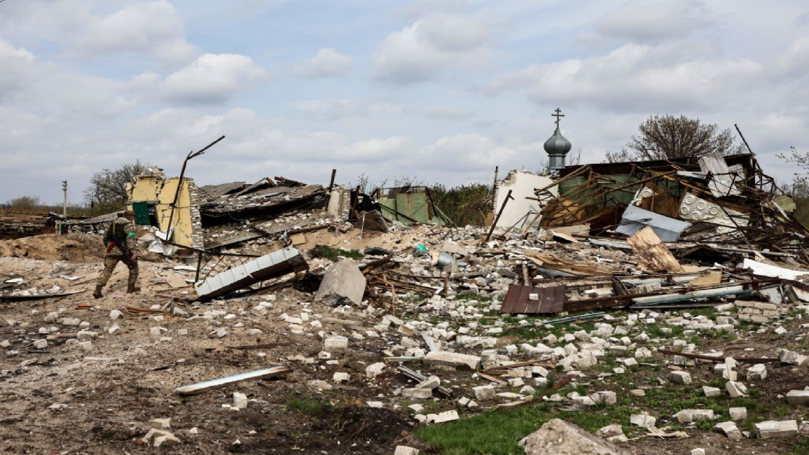 A Ukranian serviceman walks towards a destroyed house in the village of Yatskivka, eastern Ukraine