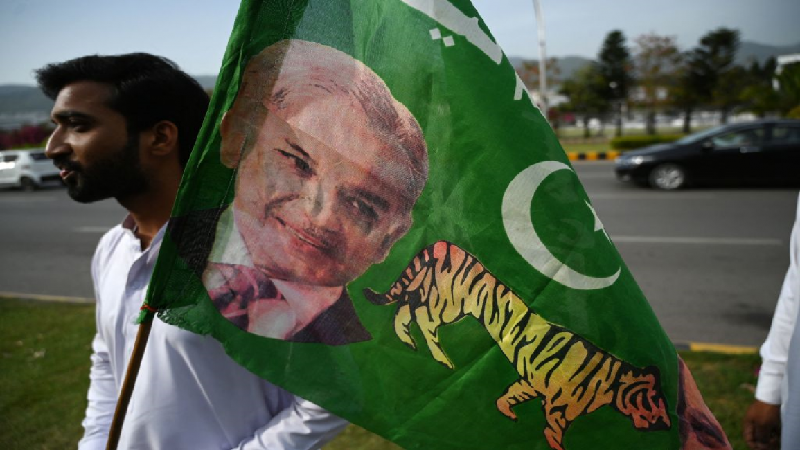 A supporter holds a party flag with an image of Shehbaz Sharif 