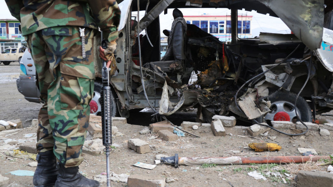 A member of Afghan security examines a minibus that has been blown up with a bomb in March 2021.