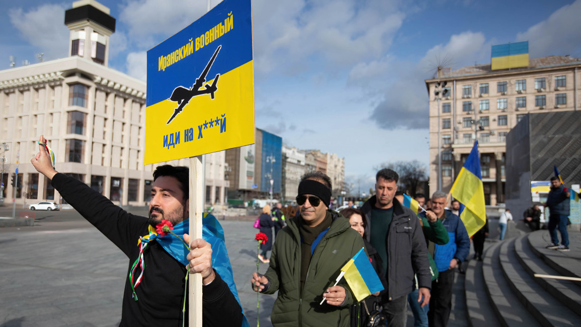  An Iranian who lives in Ukraine, holds a placard with the inscription 'Iranian military drone go f#ck yourself