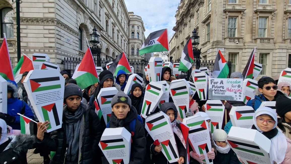 Children carrying makeshift coffins and Palestinian flags in a vigil