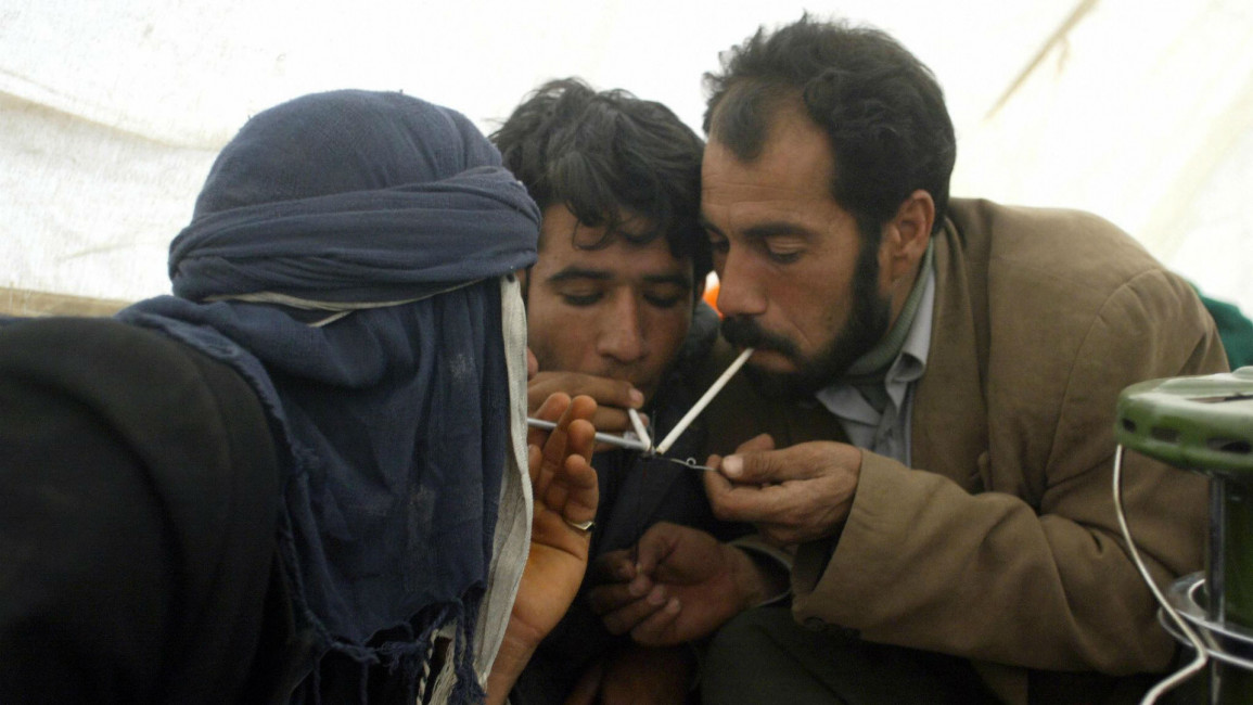 Iranian men smoke opium in a tent in 