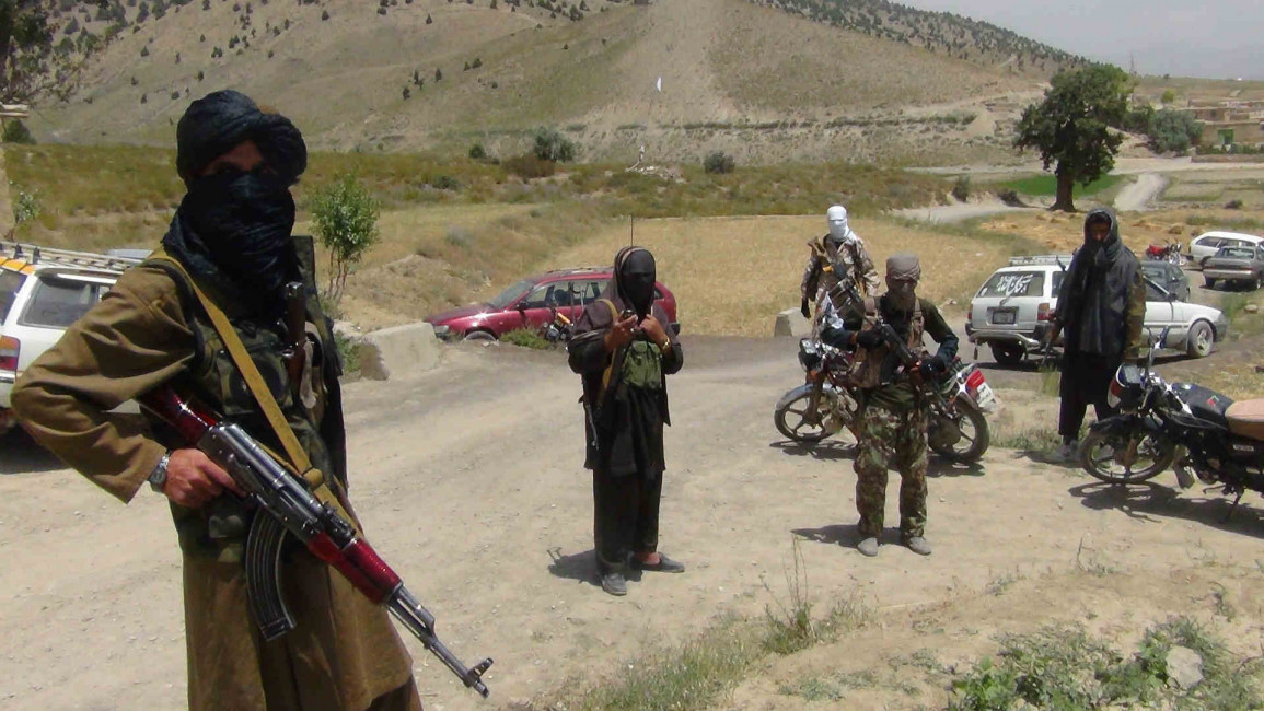Taliban fighters stand with their weapons in Afghanistan