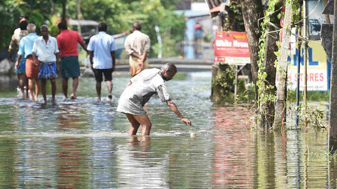 Residents wade through flood waters in Kerala