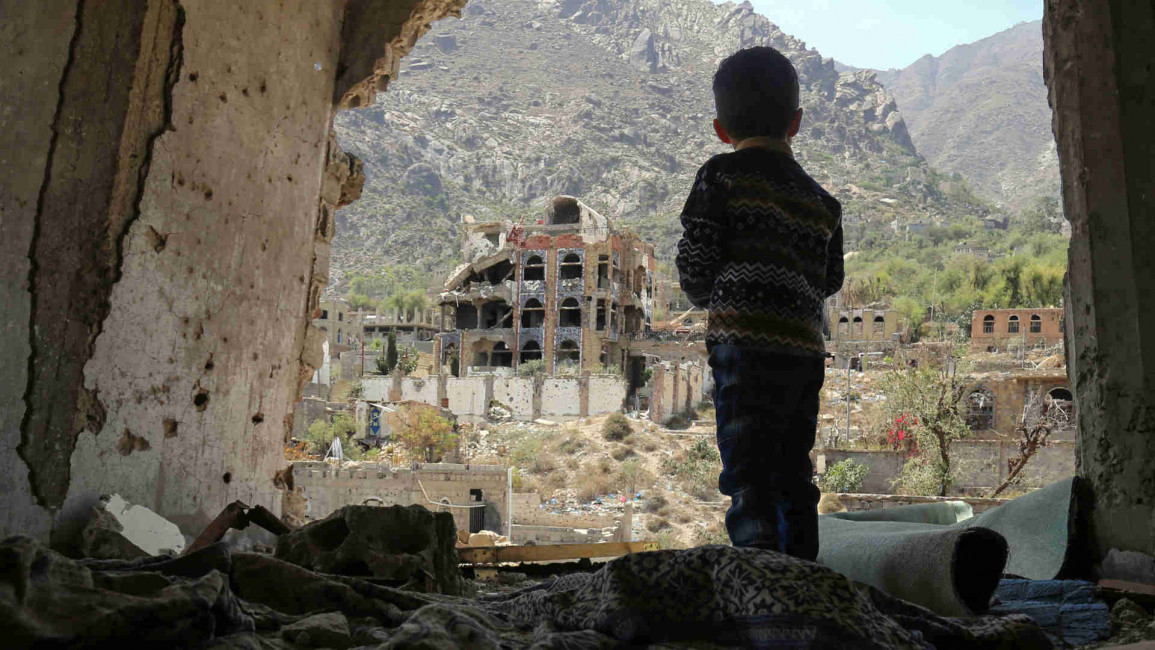 Yemeni child looking out at damaged buildings after airstrikes
