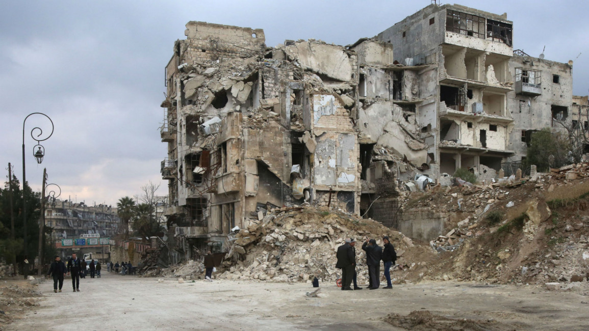 Syrians walk along a destroyed street in Aleppo [AFP]