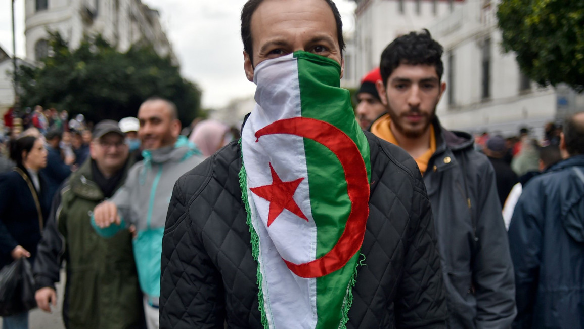 Algerians march with a national flag. [Getty[ 