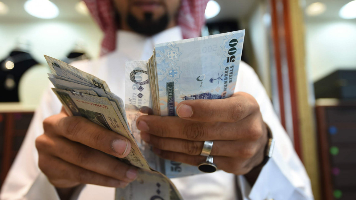 A man counts Saudi riyal banknotes in Riyadh